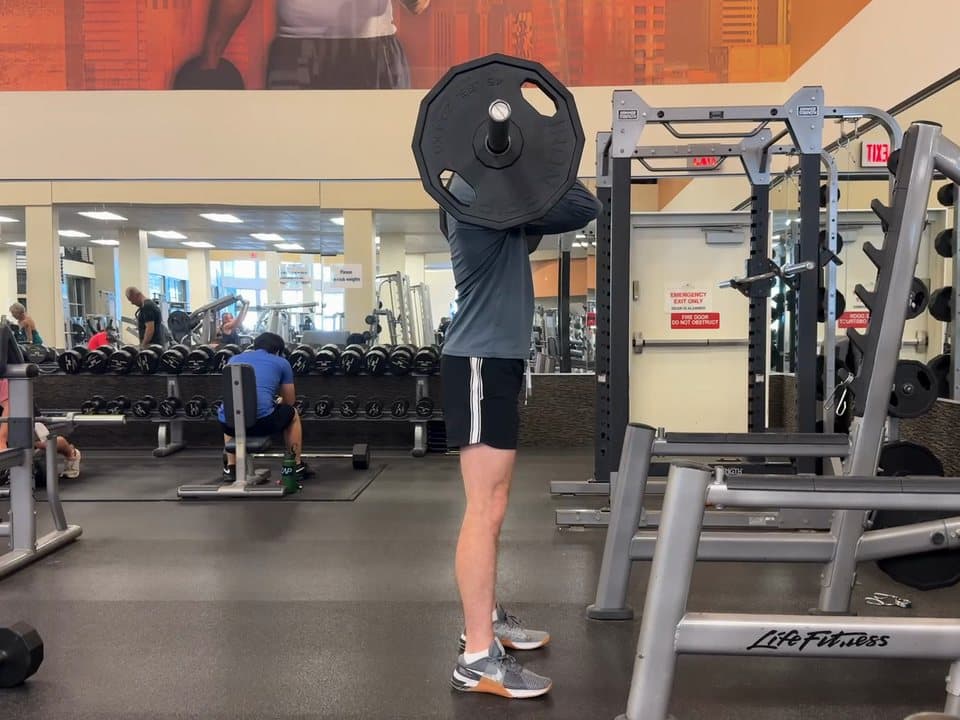 Connor Barth doing a front squat, seen from the side, the bar across the front of his shoulders.